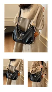 Détail du sac hobo en cuir noir avec charm ours et accessoire foulard à motifs chic