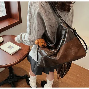 Détail d'un grand sac cabas vintage en cuir marron avec un pendentif chien en peluche