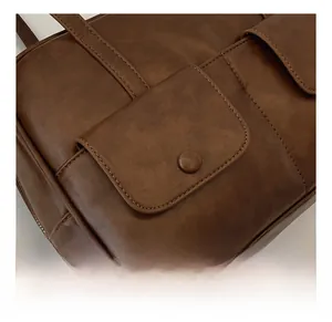 Detailed close-up of retro brown PU leather shoulder bag with pockets and fine stitching