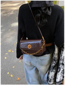 Detail of vintage dark brown leather bag with gold chain and metal lock in autumn setting