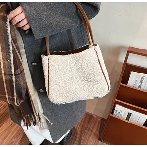 Detail of winter white faux shearling tote bag with brown leather handles and trim
