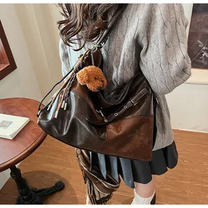 Détail d'un sac cabas vintage marron avec de longues franges et un charme d'ourson