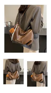 Détail d'un sac hobo en cuir marron avec breloque ours en peluche et ruban rayé