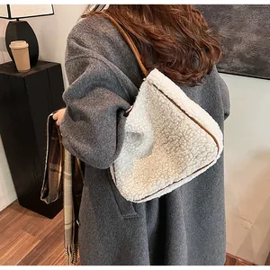 Fleece shoulder bag with leather trim shown on model in a cozy interior setting