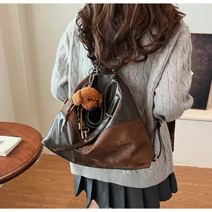 Détail d'un grand sac cabas en cuir marron avec un joli pendentif ours en peluche