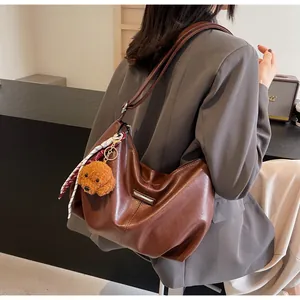 Sac hobo en cuir marron avec breloque nounours et ruban pour femme en déplacement