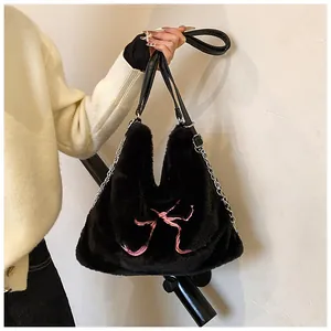 Dettaglio della borsa tote in ecopelliccia nera con fiocco rosa e catena in metallo