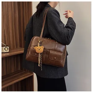 Close-up of vintage brown shoulder bag with multi-pockets and a cute teddy bear charm