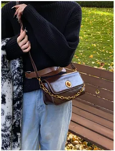 Detail of vintage coffee leather crossbody bag with gold chain and circular metal lock