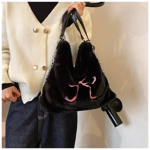 Dettaglio borsa a spalla in peluche nera con ricamo a fiocco rosa e catena argento