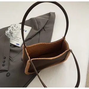 Close-up of brown faux leather shoulder bag with plush shearling trim and slim handles
