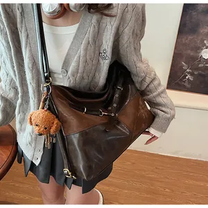 Détail du sac bandoulière rétro bicolore avec boucle en métal et breloque peluche