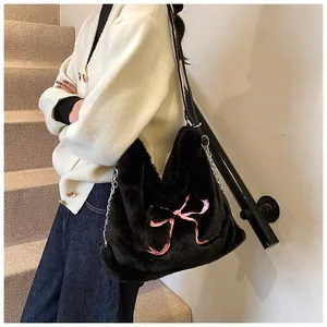 Dettaglio della borsa shopper nera in peluche con motivo a fiocco rosa e tracolla a catena