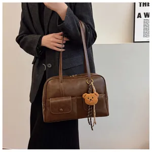 Detail view of a vintage dark brown PU leather tote bag with two front pockets and a bear charm