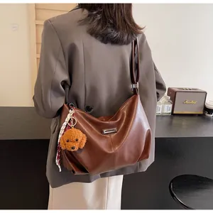 Détail d'un sac cabas en cuir PU marron avec un charmant ours en peluche et ruban