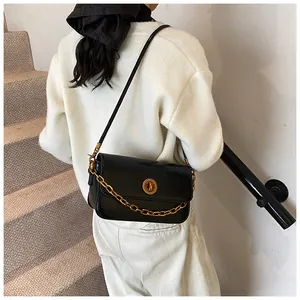 Detail of black small square shoulder bag with gold ring lock and chain strap