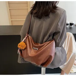 Sac hobo marron avec pendentif chien en peluche et foulard porté par un mannequin
