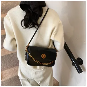 Detailed back view of a glossy black crossbody bag with gold chain and circular lock