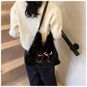 Vista posteriore della modella con borsa tote in peluche nera e fiocco rosa ricamato