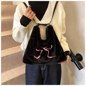 Dettaglio borsa tote in ecopelliccia nera con fiocco rosa e fibbie in metallo dorato