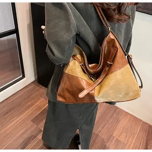 Détail d'un grand sac cabas en cuir avec patchwork marron et œillets métalliques