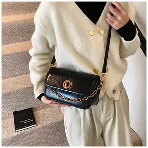 Detail of elegant black oil wax leather shoulder bag with golden round buckle and chain