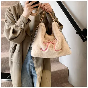 Dettaglio della borsa tote in peluche beige con ricamo a fiocco rosa e catena