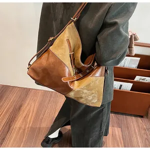 Détail d'un grand sac cabas bicolore en cuir marron et daim porté par un mannequin