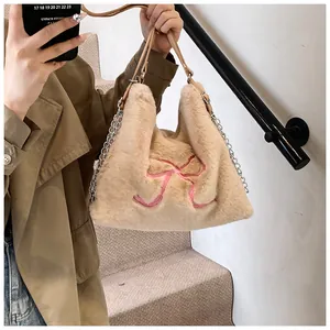 Dettaglio della borsa tote in peluche kaki con fiocco rosa ricamato e tracolla con catena