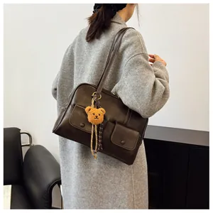 Detail of dark brown retro shoulder bag with dual front pockets and cute bear charm