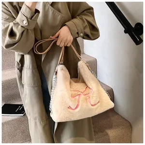 Dettaglio borsa tote in peluche beige con fiocco rosa ricamato e tracolla a catena