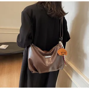 Détail du grand sac cabas demi-lune marron foncé avec plaque argentée et porte-clés chien