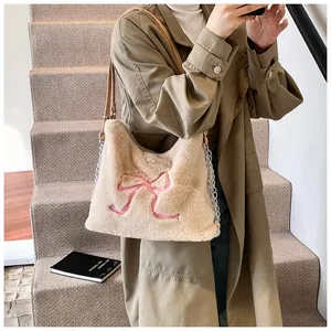 Dettaglio borsa tote beige in peluche con fiocco rosa e tracolla a catena in metallo