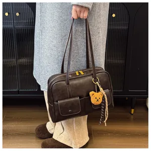 Detail view of brown vintage shoulder bag with dual utility pockets and teddy bear charm