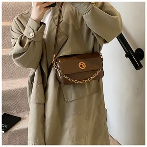 Detail of dark brown leather crossbody bag with gold round twist lock and chunky chain