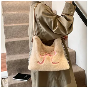 Dettaglio della borsa a spalla in peluche con ricamo a fiocco rosa e tracolla in catena