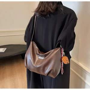 Détail du sac cabas en cuir marron foncé avec pendentif ours et plaque métallique