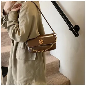 Close-up of a dark brown glossy oil wax leather shoulder bag with golden ring buckle detail