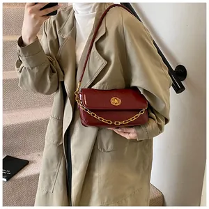 Detail of burgundy leather shoulder bag with gold chain and circular metal lock