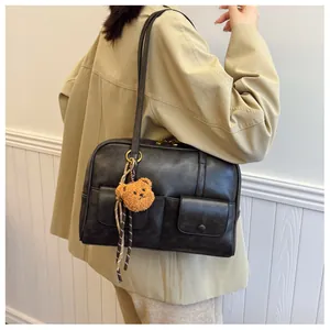 Detail of vintage black leather shoulder bag with multi-pockets and a cute bear charm