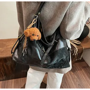 Sac à épaule noir de luxe avec boucles dorées et breloque en peluche caniche marron