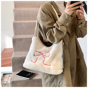 Dettaglio della borsa tote bianca in peluche con ricamo a fiocco rosa e catena in metallo