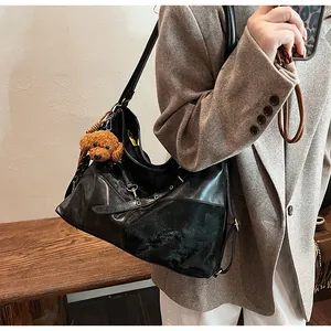 Grand sac cabas noir en similicuir avec détails zippés et breloque peluche sur un mannequin