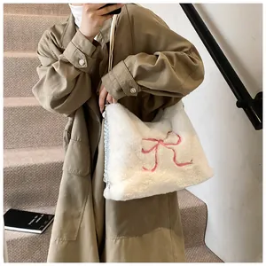 Dettaglio della borsa tote in peluche bianca con ricamo a fiocco rosa e catena