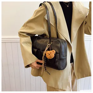 Detail of vintage black shoulder bag featuring front pocket and cute bear charm pendant