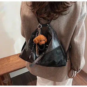 Détail du sac fourre-tout noir triangulaire en cuir avec pendentif chiot en peluche brun