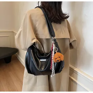 Détail du cabas en simili cuir noir avec boucles argentées et pendentif d'ours en peluche