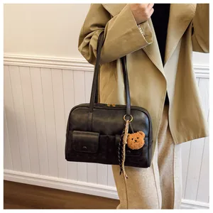 Detail of vintage black PU leather tote bag featuring functional front pockets and bear charm