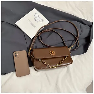 Close-up of vintage dark brown faux leather bag with gold clasp and decorative chain