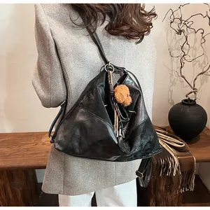 Détail du sac à bandoulière triangulaire en cuir noir avec un charm ours en peluche
